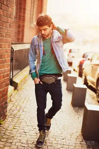 生活风格的照片一个年轻而现代的男人走在街上带着积极的微笑交叉在砖