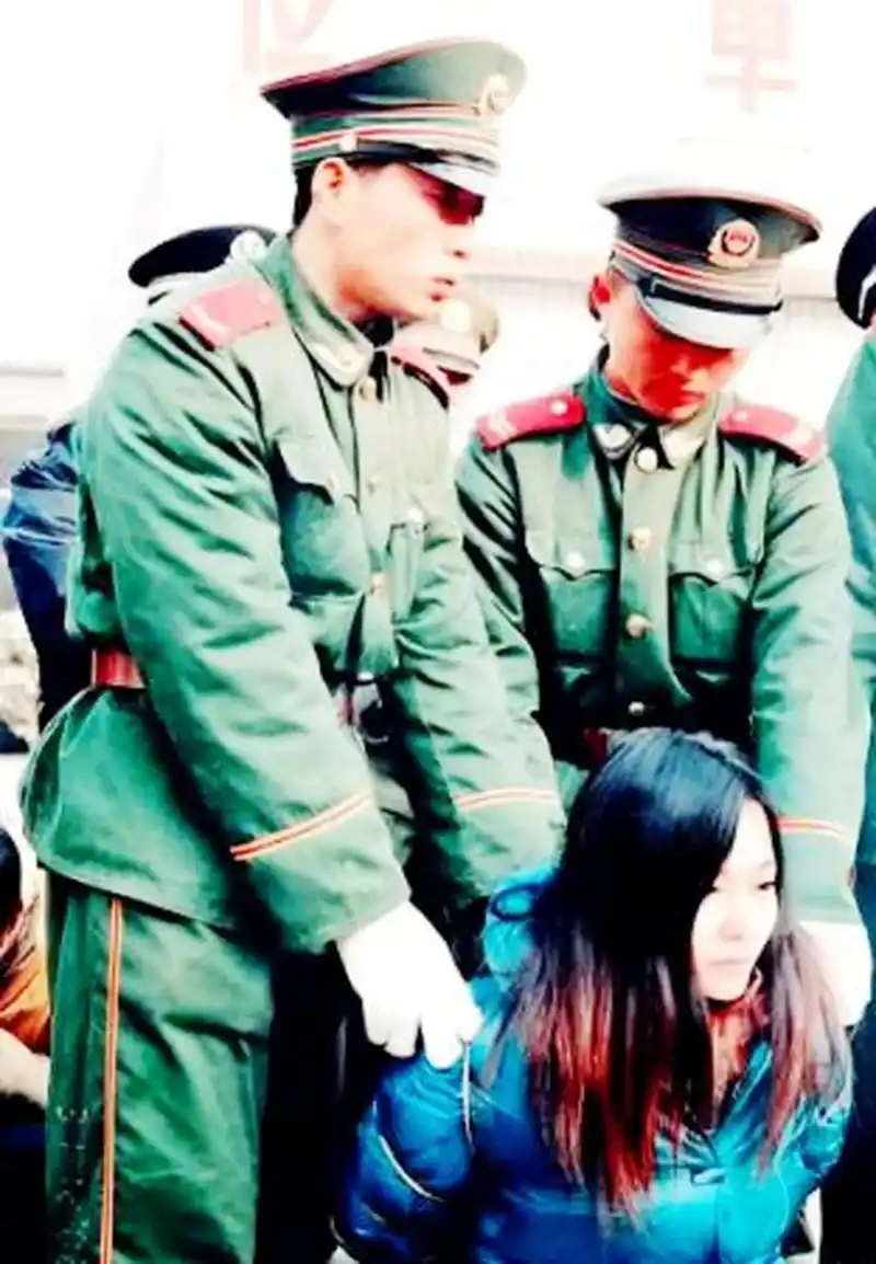 1990年代,一名年轻貌美的死刑犯被铐上手铐跪在地上等待死刑.