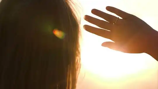 回来的女人望着远方躲在阳光下,用一只手的特写镜头