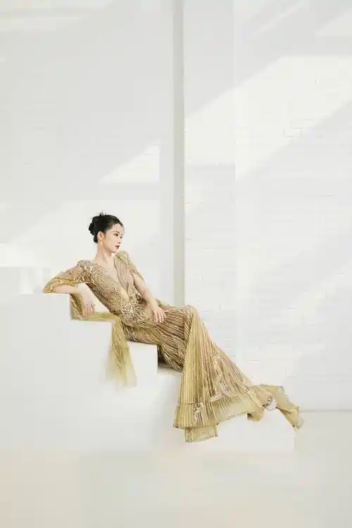 拍摄写真中,李沁身穿深v背镀金连衣裙,她站在窗边在光影下显得好美