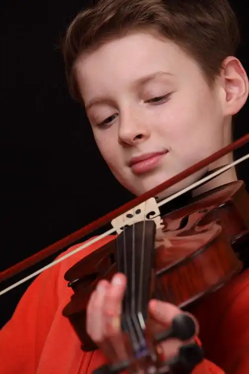 小提琴家,年轻的男孩在黑色背景上拉小提琴