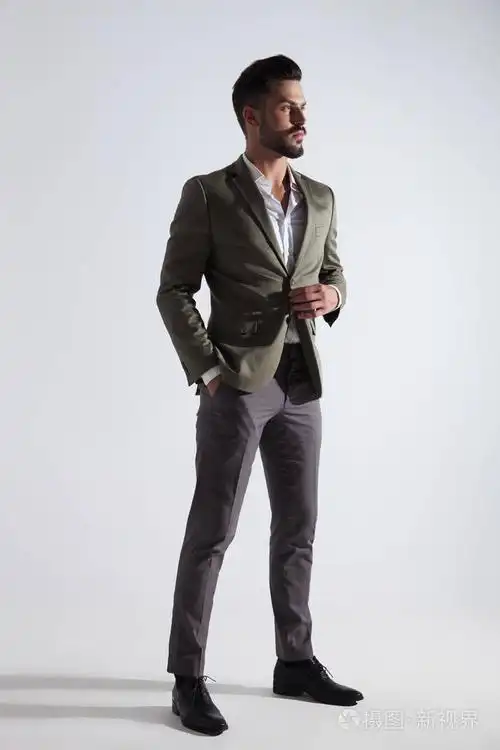 穿着灰色西装的优雅男子站在浅灰色的背景上, 看着侧面, 全长图片