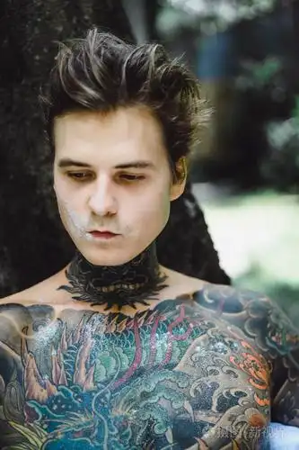 年轻英俊的纹身男在户外露天的床上吃早餐