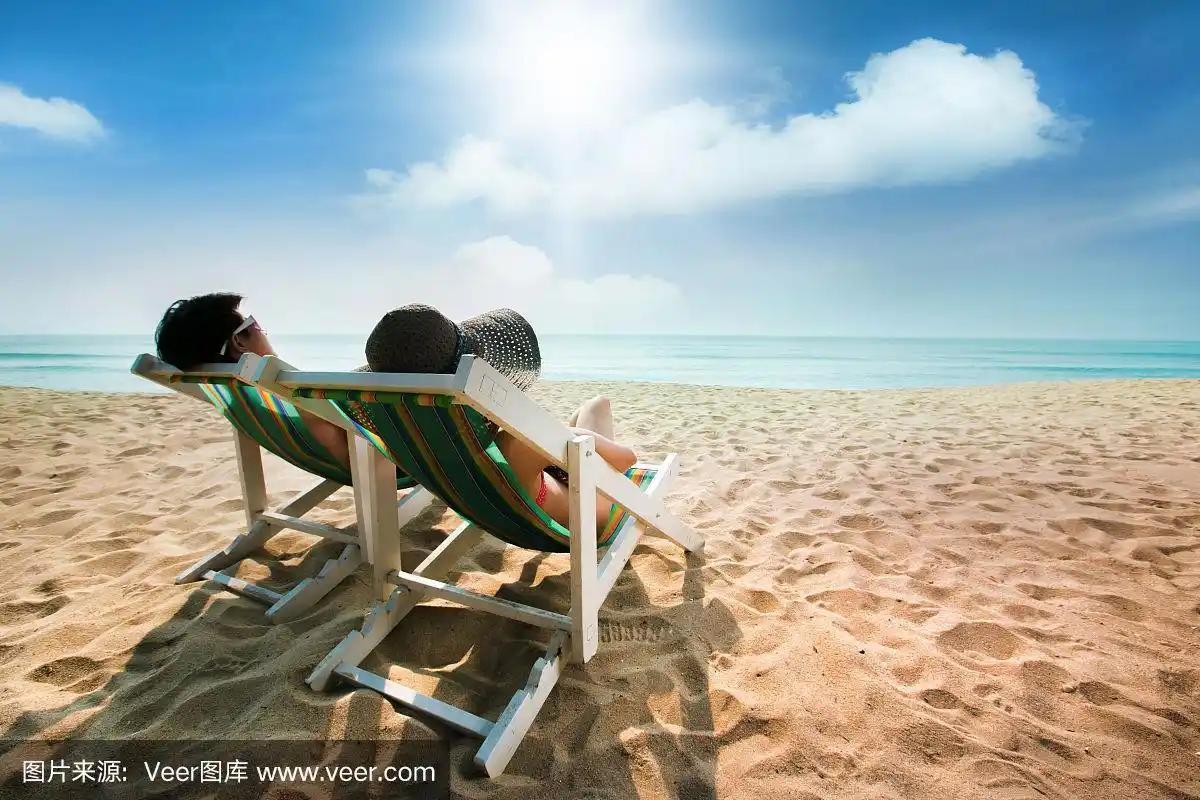 一对夫妇在沙滩椅上和伞上晒日光浴.在夏天