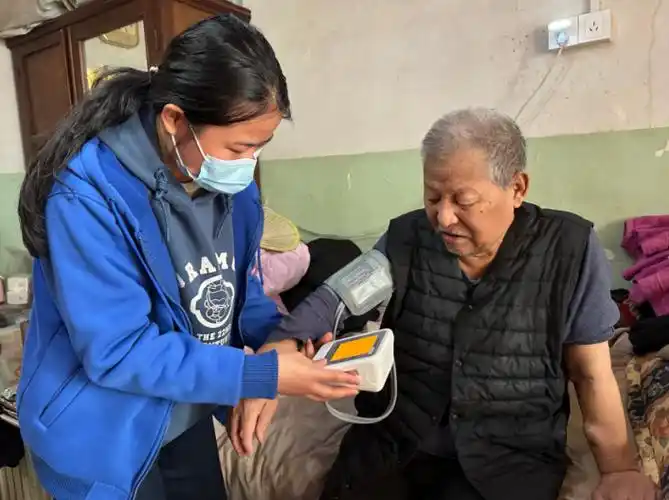 照护管理师井送杰在为老人量血压"我的脚就是泡脚的时候泡坏的.