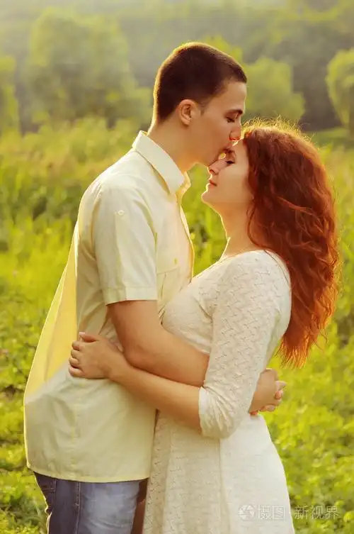 年轻的情侣在夕阳的光中拥抱