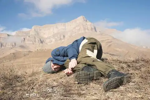 一个带着帽子和胡子的游客躺在地上, 在山上感觉很不好.失去知觉的人.