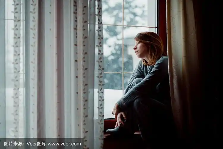 悲伤的女人坐在窗边望着外面