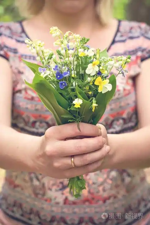 一束百合花的山谷和森林紫罗兰在一个女人的手