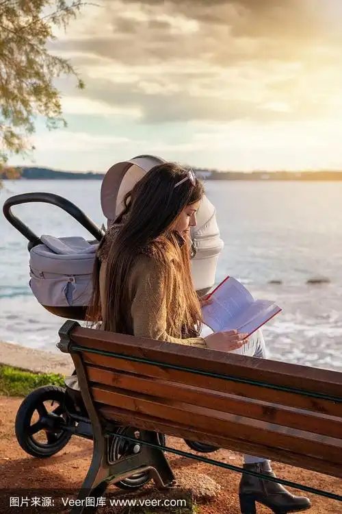 妈妈和她的孩子坐在海边的长椅上看书