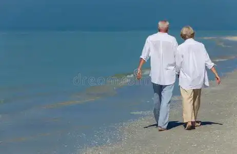 幸福的老年夫妇手牵手漫步热带海滩照片