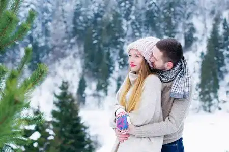 这个人从后面拥抱了那个女孩,她在冬天的山上眺望远方照片