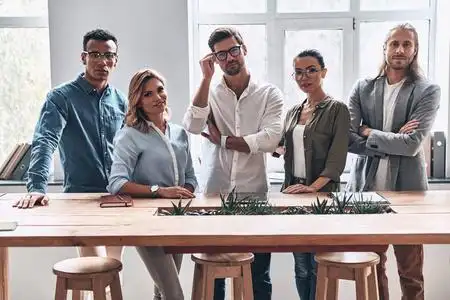 一群商务人士团队在木桌在创造性的现代办公室工作室摆姿势和看着相机