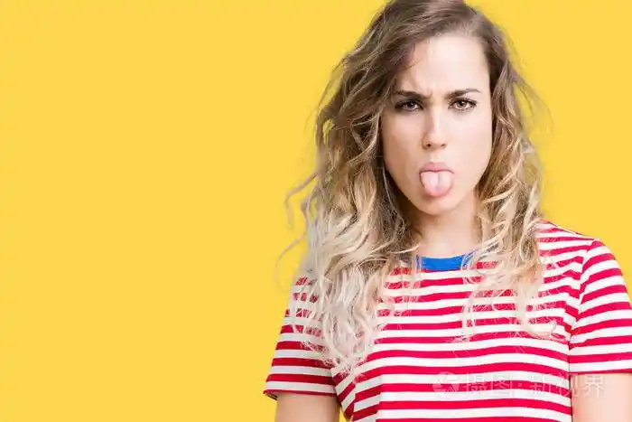 美丽的年轻金发女人在孤立的背景上伸出舌头以有趣的表情高兴情感概念