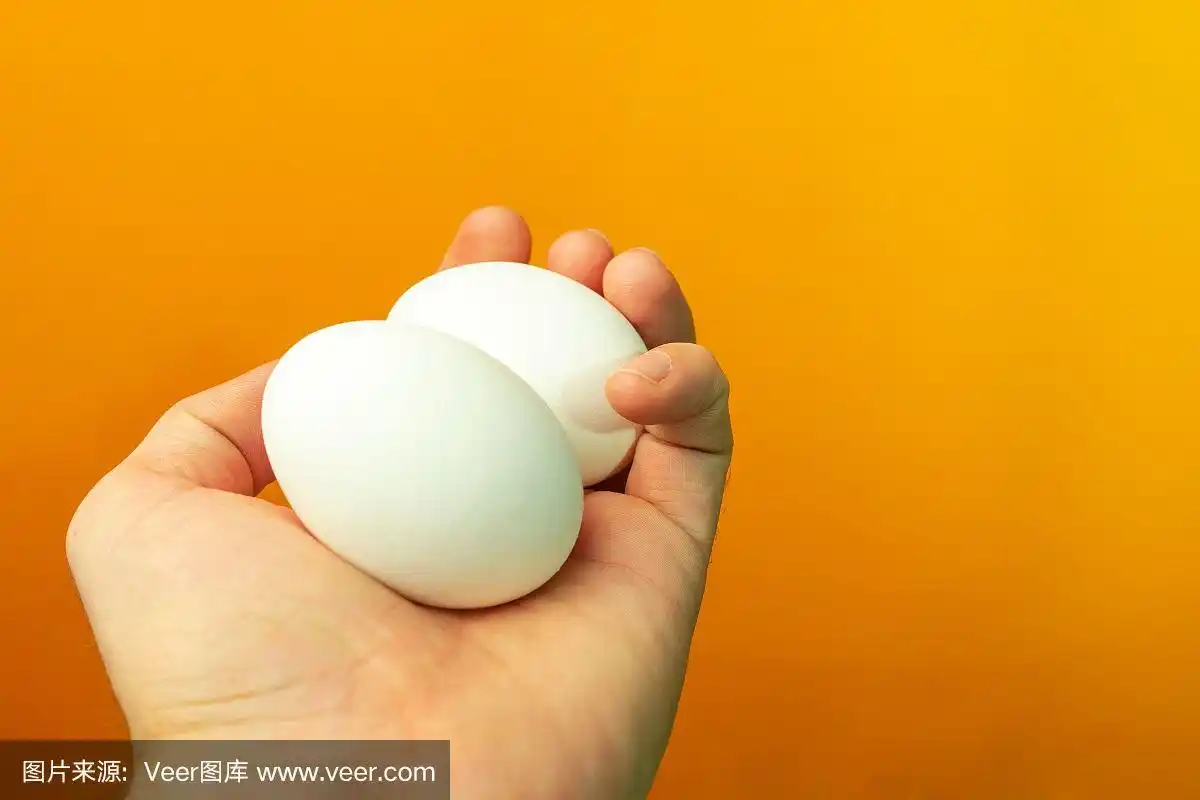 手握两个鸡蛋在橙色的背景.