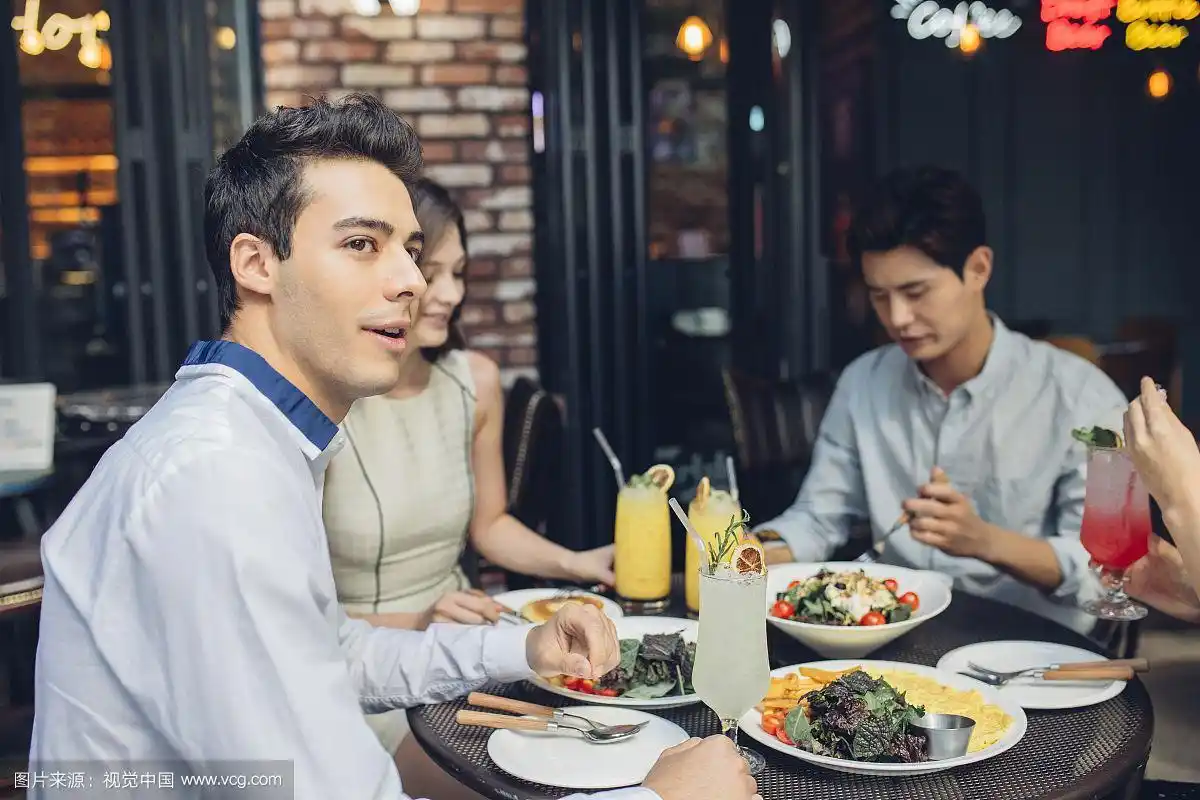 两个年轻男人和两个女人在餐厅吃饭的照片