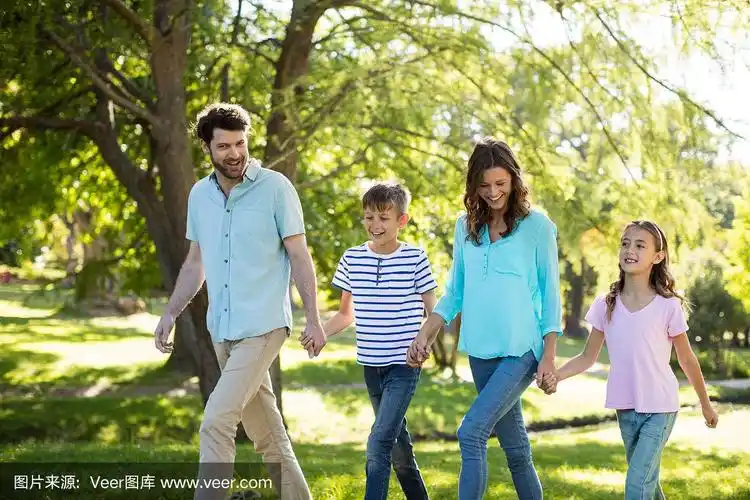 幸福的一家人手牵手在公园散步