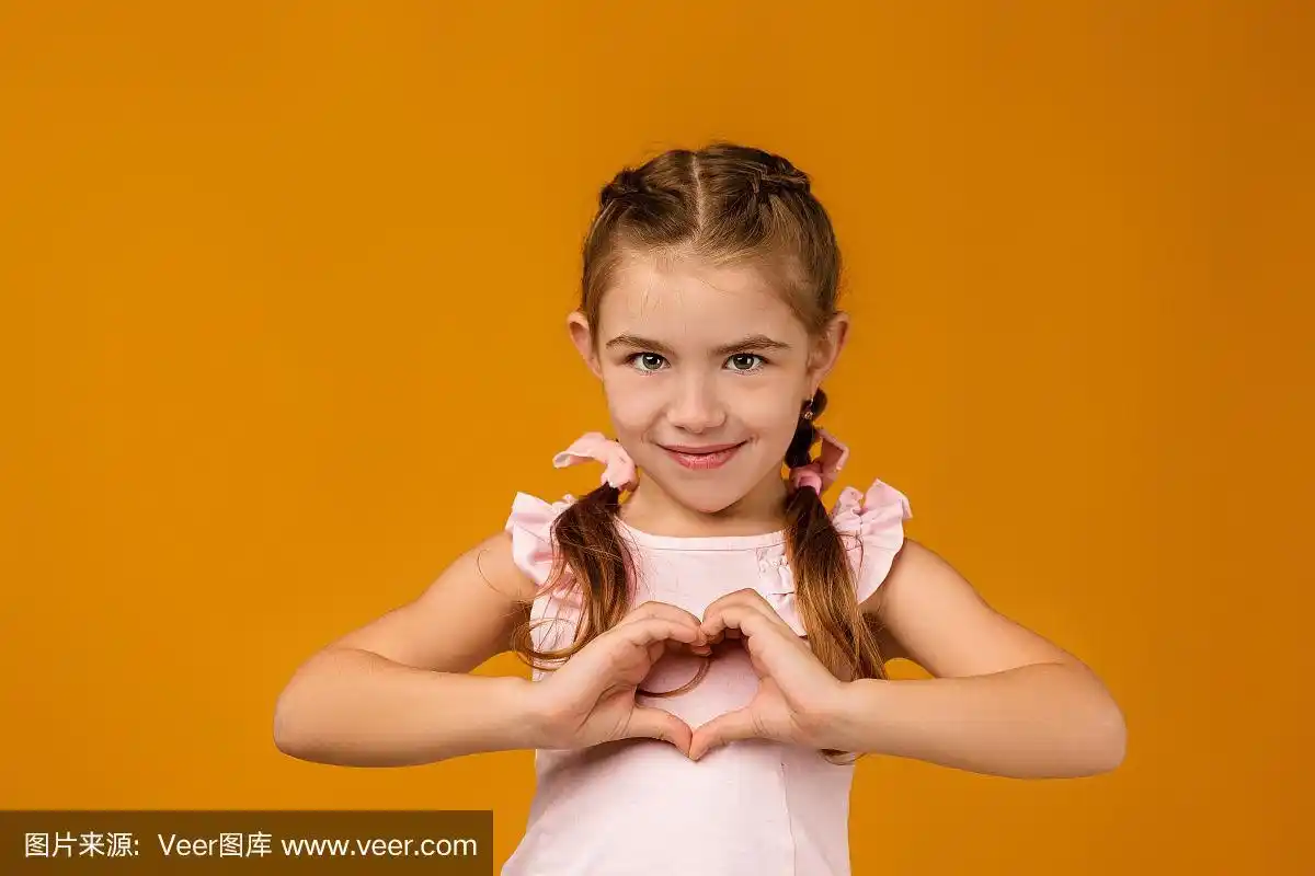 可爱的小女孩微笑着做心形的手势