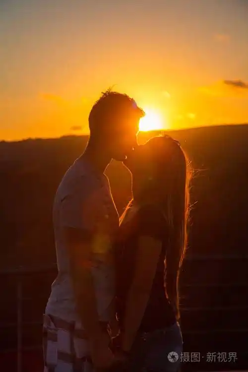 美丽的情侣在日落时接吻