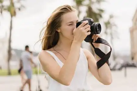 专业的女摄影师在公园里用现代的dslr相机拍照,同时在新鲜空气中漫步