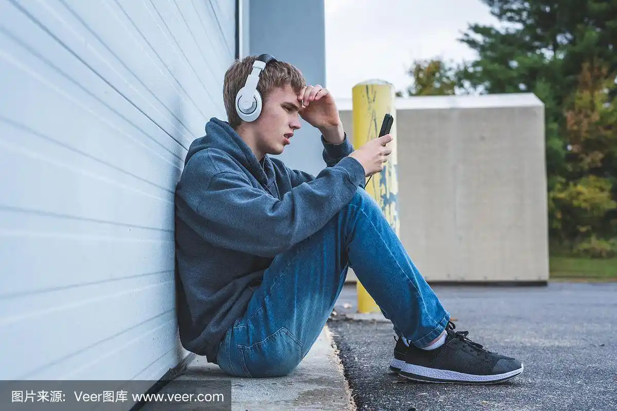 悲伤的少年戴着耳机听音乐.