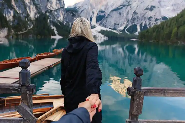 三个快乐的旅行者在一个湖上的木船在山上度假和旅游在意大利白云石的